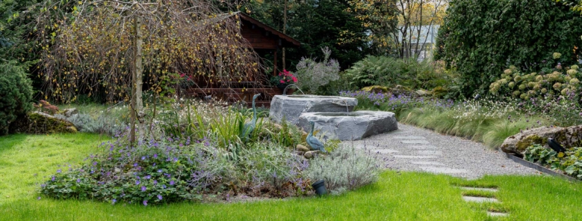 Gartenparadies mit wunderschöner Bepflanzung und Steinbrunnen